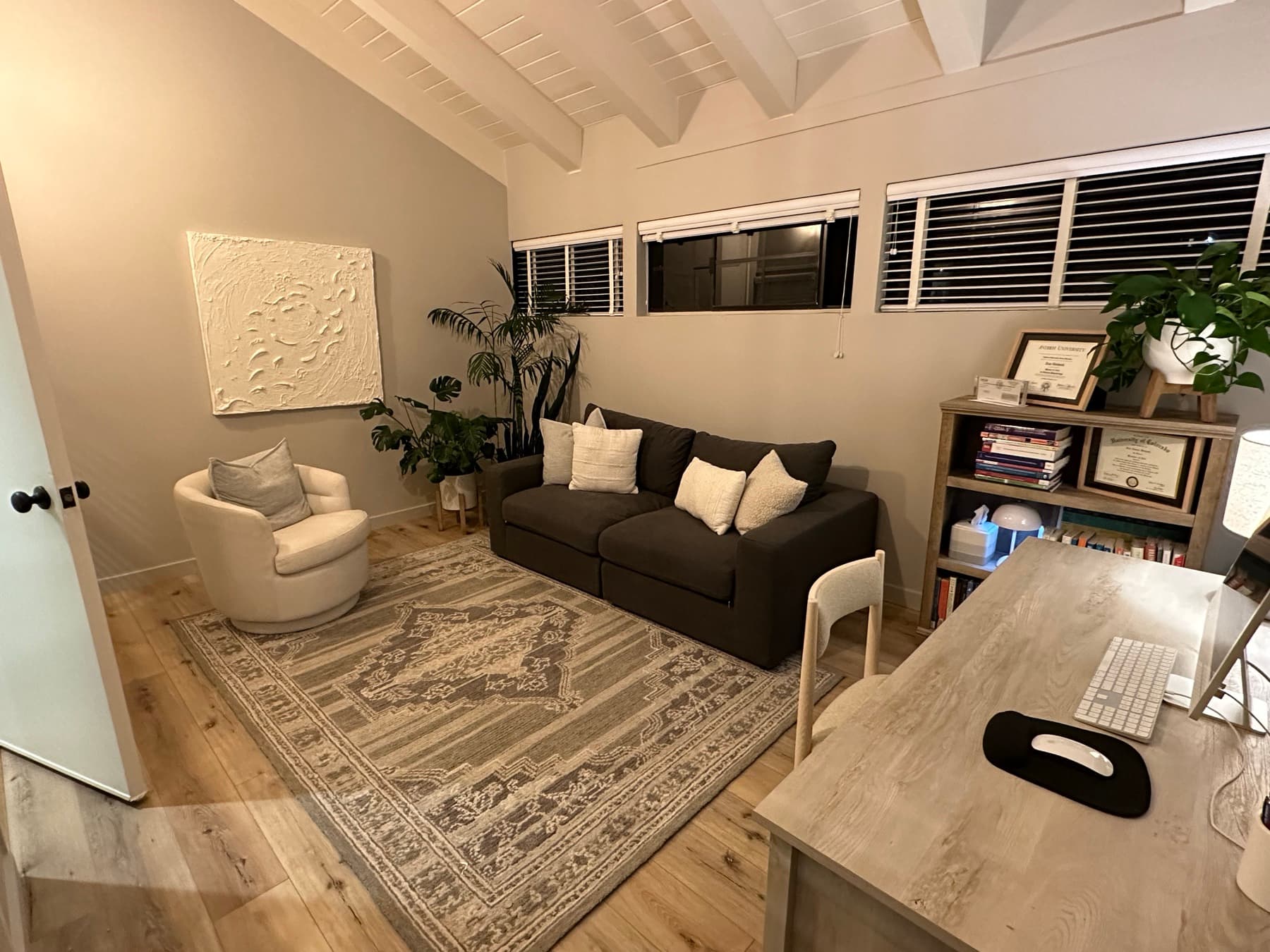 Inside the office — sofa, swivel chair, rug, and bookshelf with diplomas